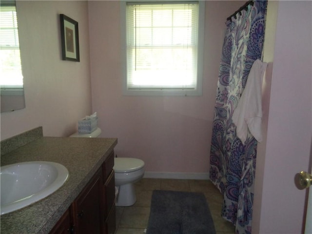 bathroom featuring healthy amount of natural light, toilet, vanity, and tile patterned floors
