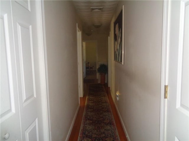 hallway featuring baseboards and wood finished floors