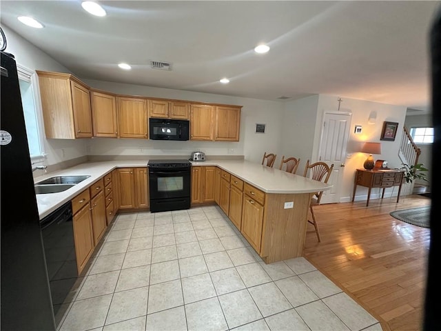 19 Calabria Ct Unit 19, Westerly, RI 02891 - kitchen with black appliances, a peninsula, a kitchen breakfast bar, a sink, and light countertops