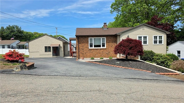57 Boundary Ave, Providence, RI 02909 - view of front of house with brick siding, asphalt driveway, a chimney, and fence