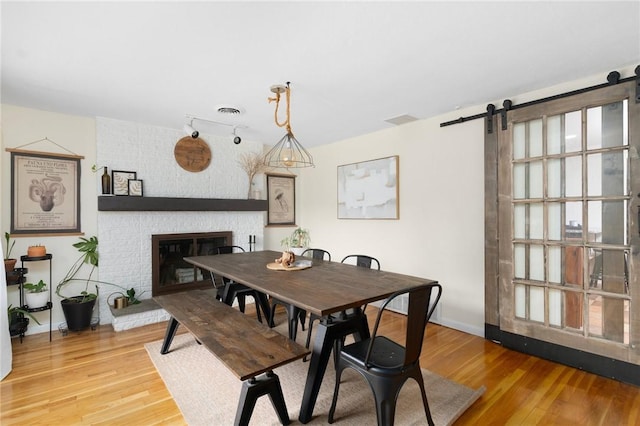 37 Charles St, Barrington, RI 02806 - dining room with a barn door, a brick fireplace, wood finished floors, and baseboards