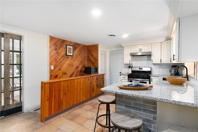 37 Charles St, Barrington, RI 02806 - kitchen with appliances with stainless steel finishes, a sink, under cabinet range hood, light stone countertops, and a peninsula