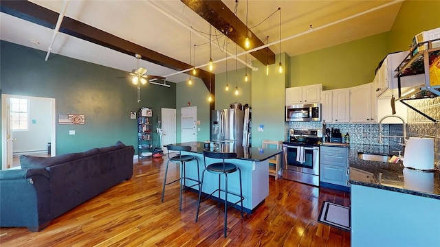 kitchen with stainless steel appliances, a sink, ceiling fan, white cabinets, and a kitchen breakfast bar