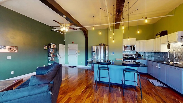 kitchen featuring appliances with stainless steel finishes, a sink, open floor plan, dark countertops, and high vaulted ceiling
