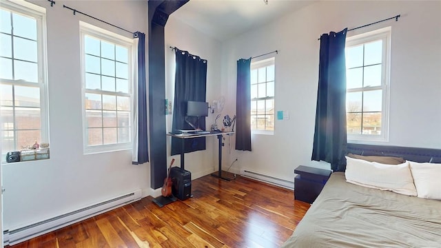 bedroom featuring a baseboard heating unit, wood finished floors, and baseboards