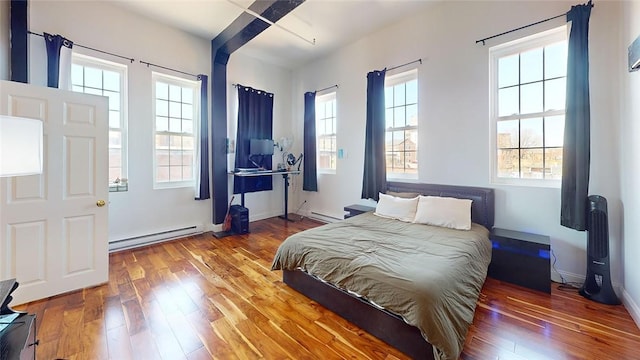 bedroom with a baseboard radiator, hardwood / wood-style flooring, and baseboards