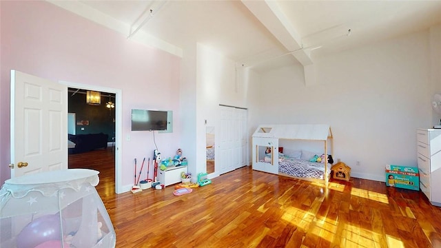 bedroom featuring wood finished floors, a high ceiling, and baseboards
