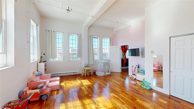 entrance foyer with baseboard heating, a high ceiling, and wood finished floors