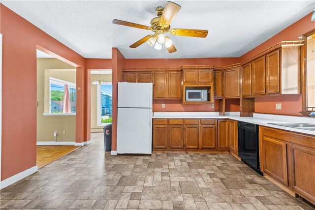 kitchen with freestanding refrigerator, dishwasher, stainless steel microwave, brown cabinetry, and baseboards