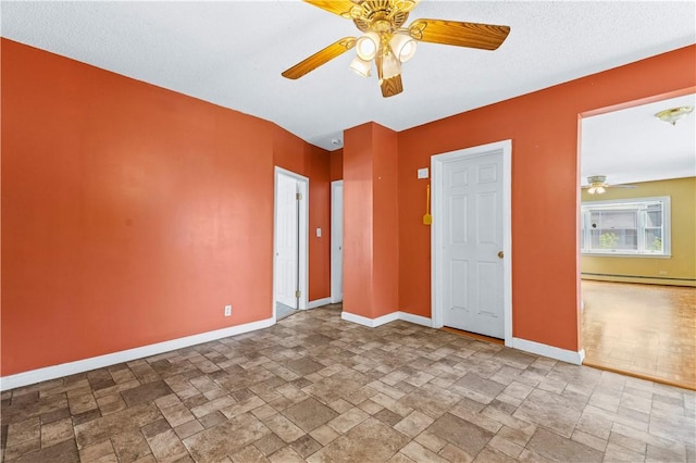 unfurnished bedroom featuring stone tile floors, baseboards, a ceiling fan, and a baseboard radiator