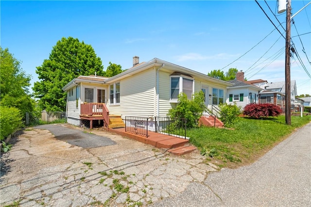view of side of home with a chimney, a wooden deck, and fence