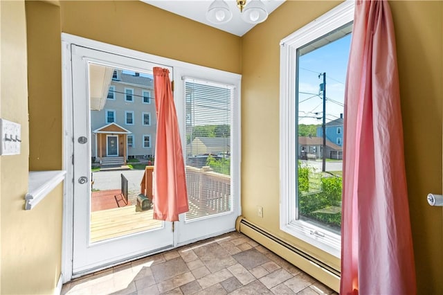 entryway featuring a baseboard heating unit, healthy amount of natural light, stone finish flooring, and a chandelier