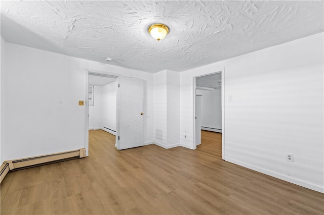 empty room featuring a baseboard radiator, wood finished floors, baseboards, and a textured ceiling