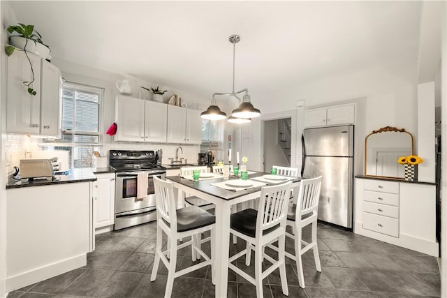 33 Marsh St Unit 1, Newport, RI 02840 - kitchen with stainless steel appliances, dark countertops, white cabinetry, decorative backsplash, and decorative light fixtures