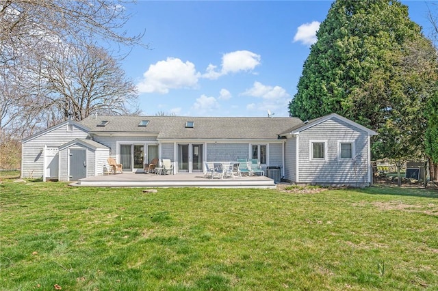 rear view of house featuring a shed, an outbuilding, a deck, and a yard