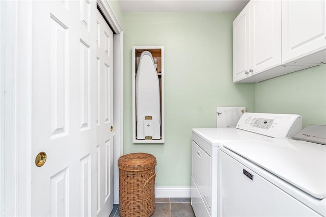 clothes washing area with cabinet space, washing machine and clothes dryer, baseboards, and tile patterned floors