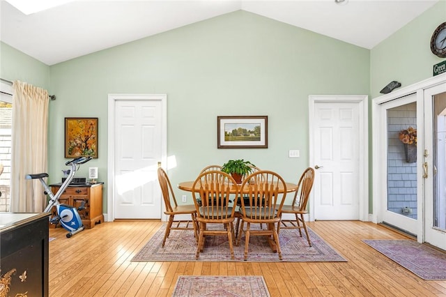 dining area featuring light wood finished floors, high vaulted ceiling, and baseboards