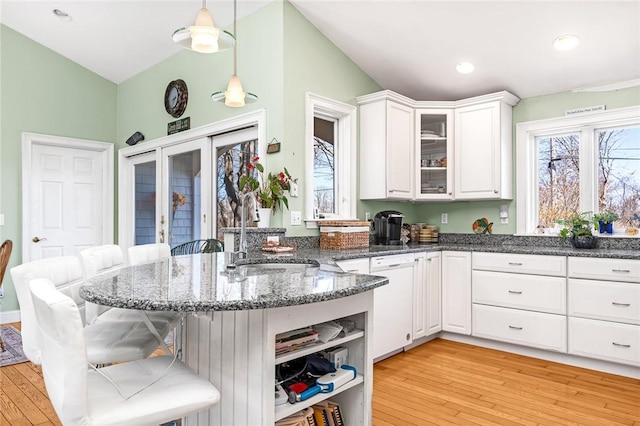 kitchen with a sink, a kitchen bar, white cabinets, plenty of natural light, and vaulted ceiling