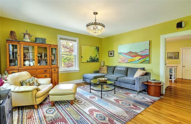 living room with wood finished floors, a chandelier, and baseboards