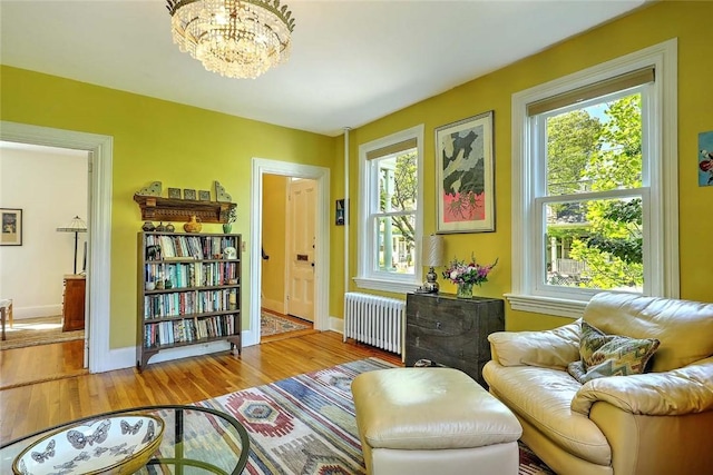 living area featuring radiator, healthy amount of natural light, wood finished floors, and a chandelier