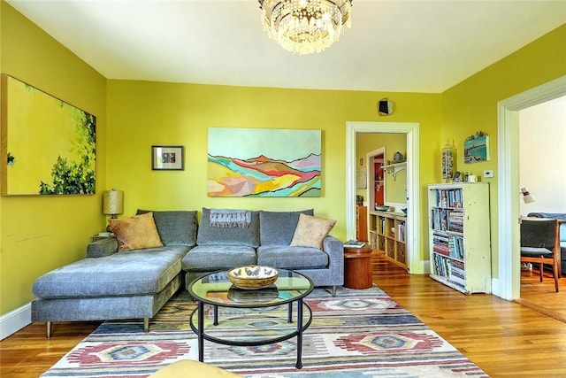 living room featuring wood finished floors, a chandelier, and baseboards