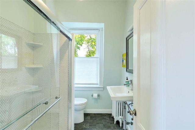 bathroom featuring toilet, a stall shower, and baseboards