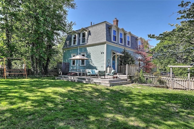 rear view of property with mansard roof, a chimney, a wooden deck, and an outdoor hangout area