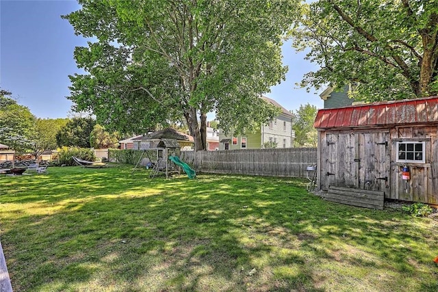 view of yard with a playground, a storage unit, and an outbuilding