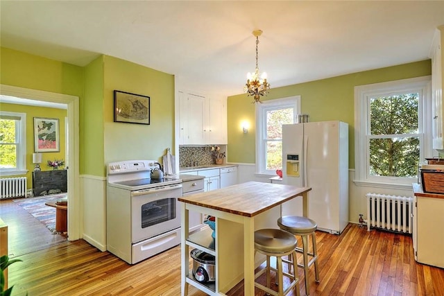 kitchen with radiator, white appliances, butcher block counters, and white cabinets