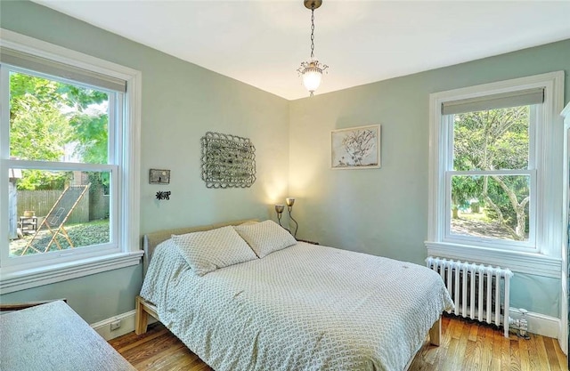 bedroom featuring radiator, multiple windows, and baseboards