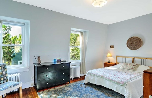 bedroom with radiator heating unit, dark wood-style flooring, and baseboards