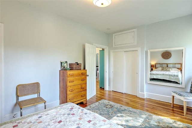 bedroom with wood finished floors, baseboards, and a closet