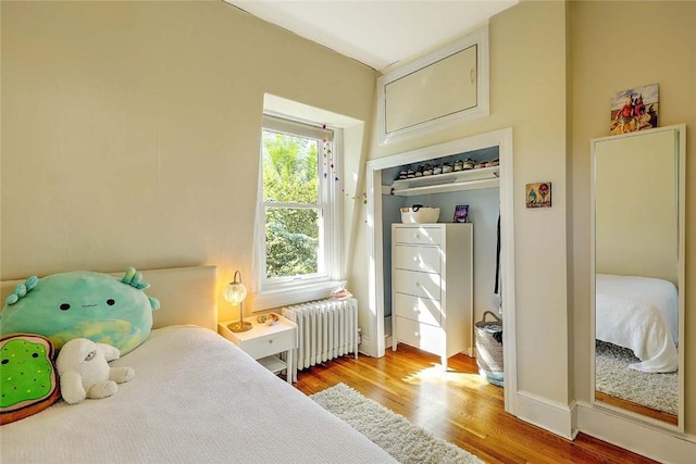bedroom with radiator heating unit and wood finished floors