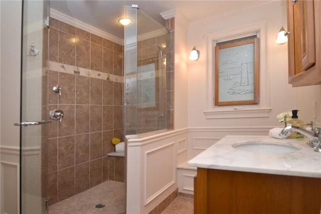 244 Kingstown Rd, Narragansett, RI 02882 - bathroom featuring crown molding, a decorative wall, a tile shower, vanity, and wainscoting