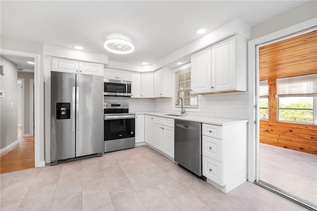 kitchen with appliances with stainless steel finishes, a sink, light countertops, tasteful backsplash, and recessed lighting