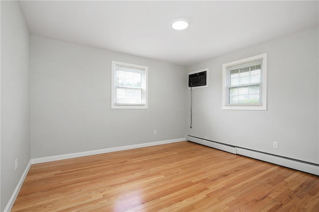 unfurnished room with plenty of natural light, a baseboard heating unit, light wood-style floors, and baseboards