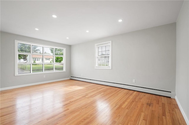 unfurnished room featuring a baseboard heating unit, light wood-type flooring, recessed lighting, and baseboards