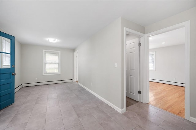 spare room featuring a baseboard radiator, light tile patterned floors, and baseboards