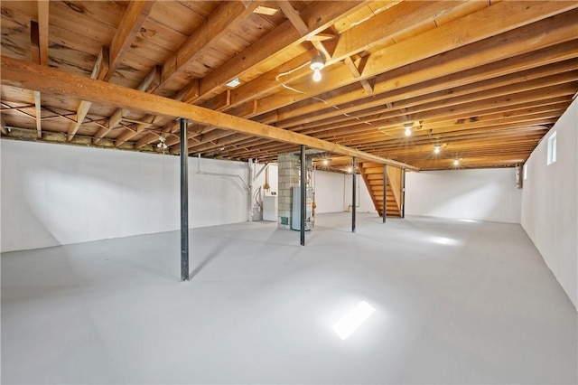 unfinished basement featuring stairs and gas water heater
