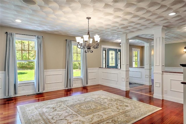 26 Old Richmond Townhouse Rd, Richmond, RI 02812 - dining area with ornate columns, a chandelier, a wainscoted wall, wood finished floors, and a decorative wall