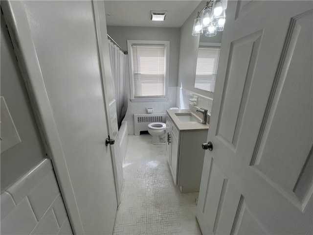 bathroom with radiator, vanity, toilet, tile patterned floors, and a wainscoted wall
