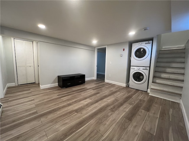 washroom featuring estacked washer and dryer, wood finished floors, baseboards, and recessed lighting