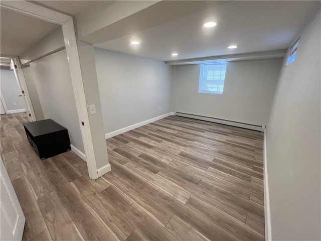 below grade area featuring a baseboard heating unit, wood finished floors, baseboards, and recessed lighting