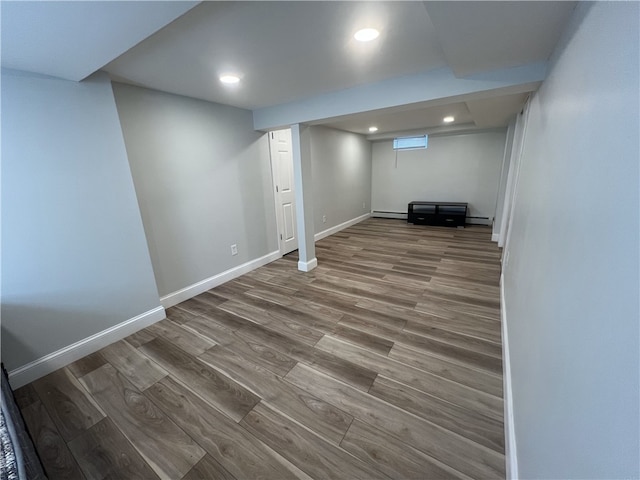 finished basement featuring wood finished floors, baseboards, recessed lighting, and a baseboard heating unit