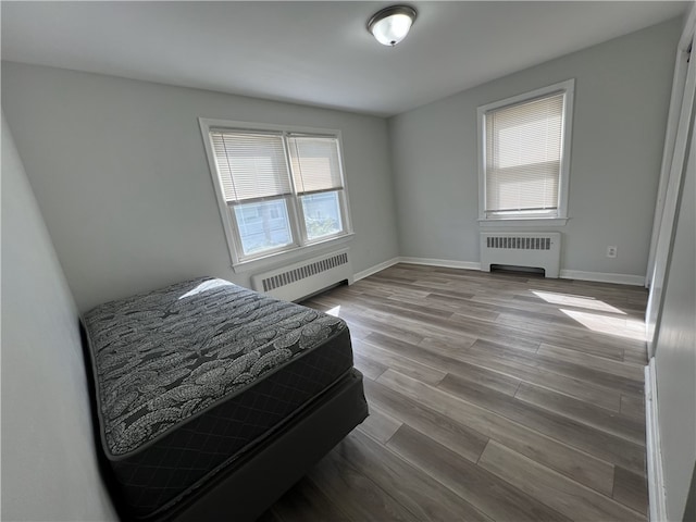 bedroom featuring radiator, wood finished floors, and baseboards