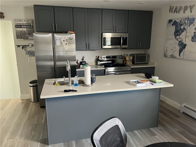 kitchen featuring stainless steel appliances, light wood finished floors, light countertops, and baseboards