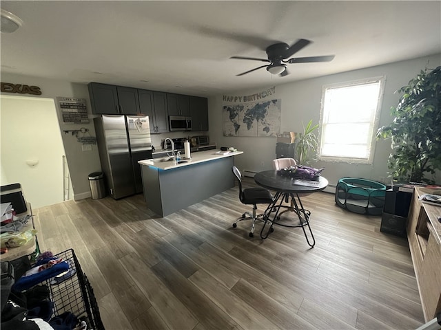 kitchen with appliances with stainless steel finishes, ceiling fan, light countertops, a sink, and wood finished floors