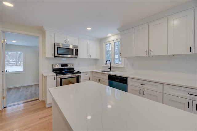 247 Quaker Ln, Scituate, RI 02857 - kitchen featuring stainless steel appliances, a sink, light wood-type flooring, decorative backsplash, and white cabinets