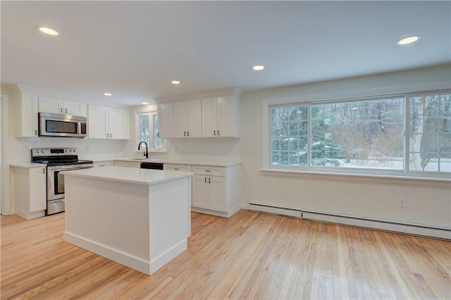 247 Quaker Ln, Scituate, RI 02857 - kitchen with appliances with stainless steel finishes, a baseboard heating unit, white cabinetry, light countertops, and light wood-style flooring