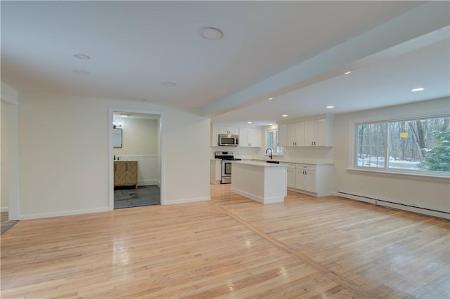 247 Quaker Ln, Scituate, RI 02857 - unfurnished living room featuring baseboard heating, light wood-type flooring, a sink, baseboards, and recessed lighting